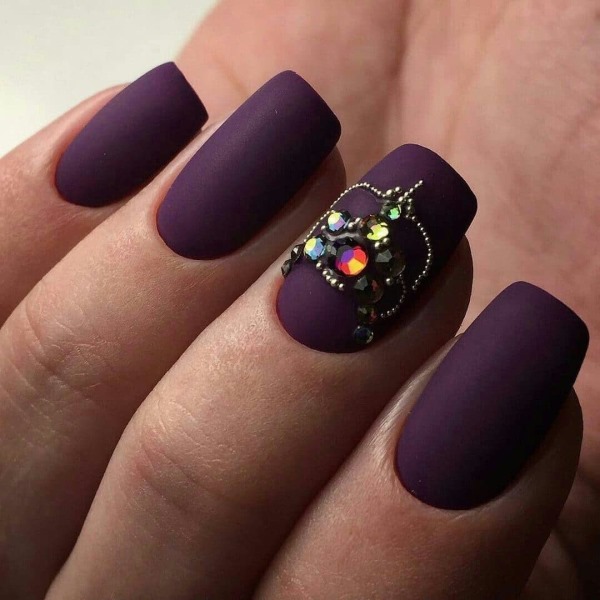 Desenho de unhas roxo. Foto com uma imagem, strass, brilhos, esfregando