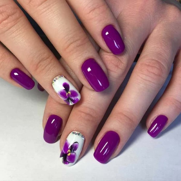 Desenho de unhas roxo. Foto com uma imagem, strass, brilhos, esfregando