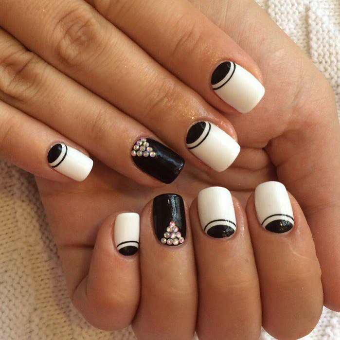 Conception d'ongles en noir et blanc. Photo de nouveaux articles avec strass, argent, veste de service, or, motif