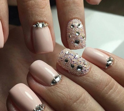 Manicure em tons de marrom-bege. Foto com um padrão, com strass para unhas curtas e compridas