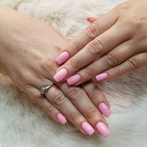 Desenhos de unhas de manicure nas cores rosa. Foto com uma imagem, strass, brilhos