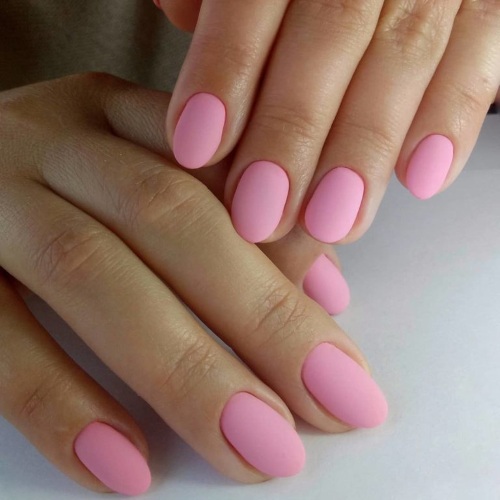 Desenhos de unhas de manicure nas cores rosa. Foto com uma imagem, strass, brilhos