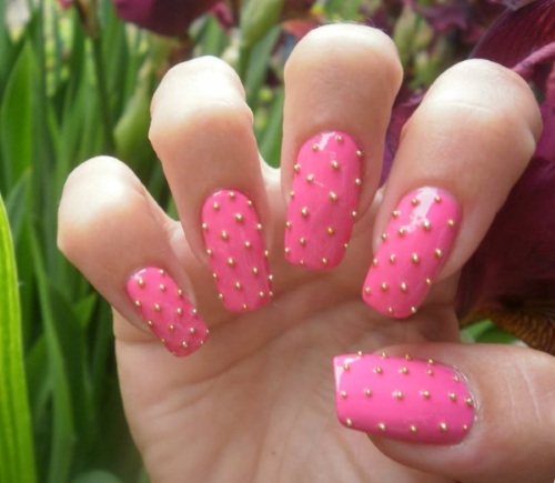 Desenhos de unhas de manicure nas cores rosa. Foto com uma imagem, strass, brilhos