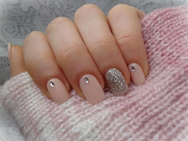 Manicure bege com brilhos, strass nas unhas curtas na base, fricção, estampa. Uma foto