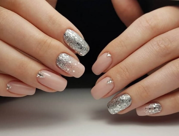 Manicure bege com brilhos, strass nas unhas curtas na base, fricção, estampa. Uma foto