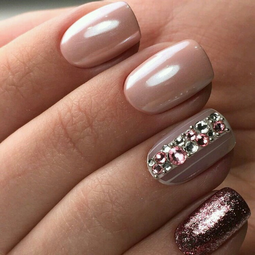 Manicure bege com brilhos, strass nas unhas curtas na base, fricção, estampa. Uma foto