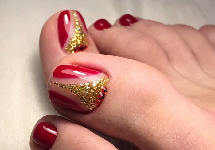 Pedicure vermelha nos pés. Foto com desenho, strass, padrões, esfregando