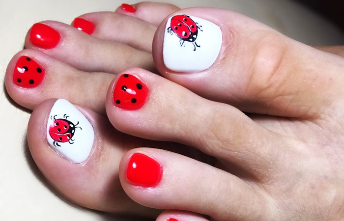 Pedicure vermelha nos pés. Foto com desenho, strass, padrões, esfregando