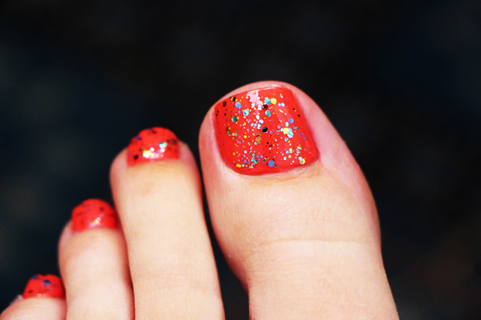 Pedicure vermelha nos pés. Foto com desenho, strass, padrões, esfregando