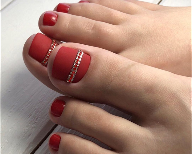 Pedicure vermelha nos pés. Foto com desenho, strass, padrões, esfregando